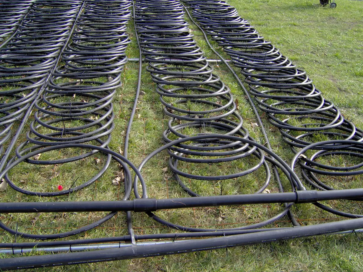 Coiled HDPE ground loop pipe for a 12-ton geothermal heat pump system laid out on grass